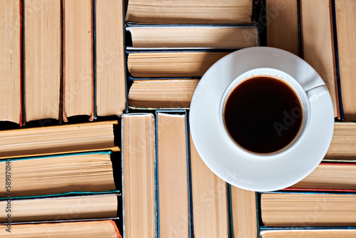 A cup of coffee stands on folded hardcover books, top view. Educational concept. Up close