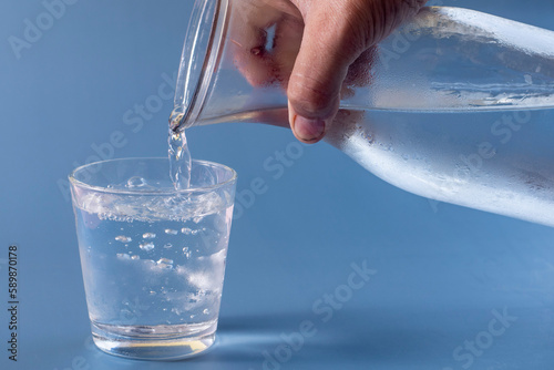 Glass of water being filled on blue background