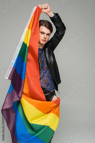 young and fashionable pansexual model posing with lgbt flag isolated on grey.