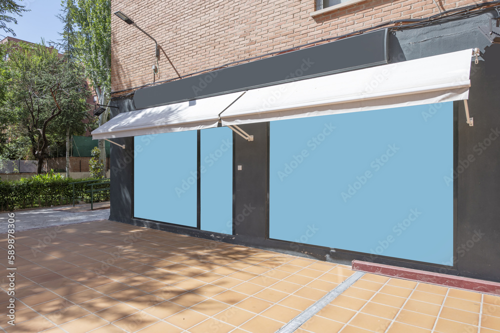 Gray facade of a commercial premises with awnings in the basement of a building with excess trees Gray facade of a commercial premises with awnings in the basement of a building with excess trees
