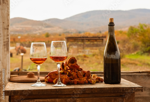 on the old table there is a bottle of wine, two glasses and dried fruit