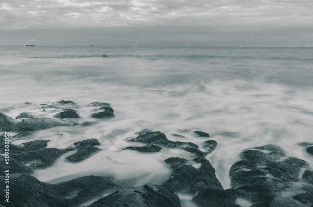 A beautiful long exposure shot of waves crashing onto the rocky shore