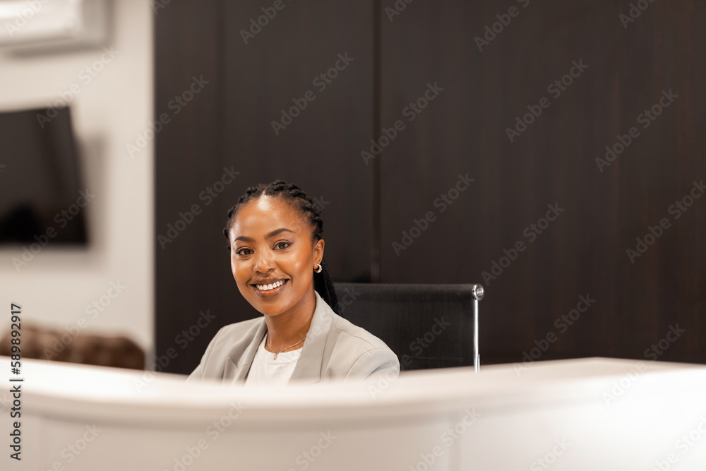 The young African American female receptionist sits behind the