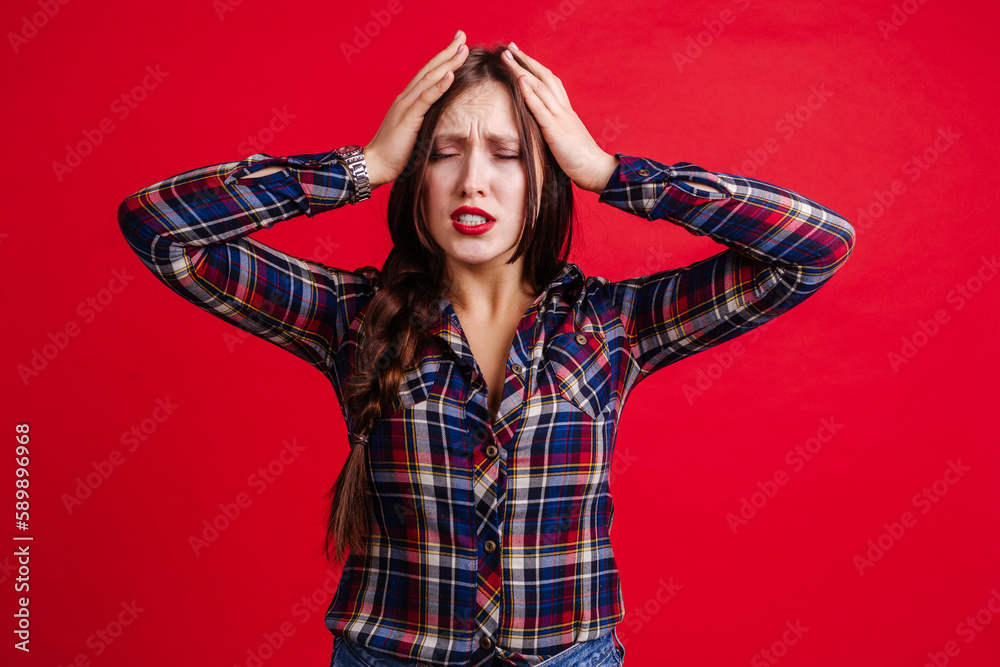 Girl holding on to her head standing on a red background Girl holding on to her head standing on a red background