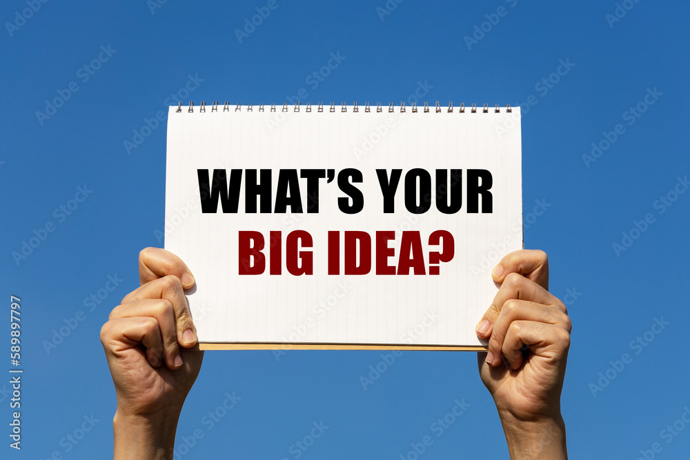 What's your big idea text on notebook paper held by 2 hands with isolated blue sky background. This message can be used as business concept about big idea. What's your big idea text on notebook paper held by 2 hands with isolated blue sky background. This message can be used as business concept about big idea.