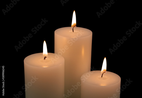 Close up of three white candles isolated on black background. 