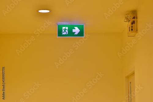 Green emergency exit sign showing the way to escape. Fire exit in the building.