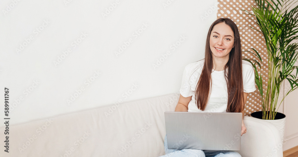 Girl sitting on sofa with laptop smiling and looking at camera web banner Girl sitting on sofa with laptop smiling and looking at camera web banner