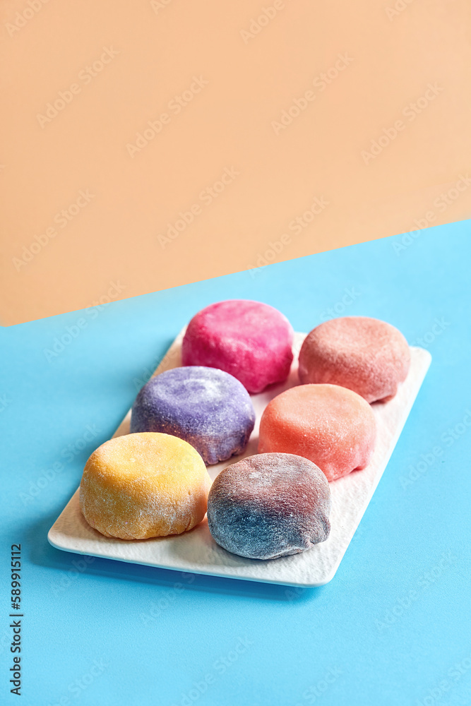 Japanese mochi desserts with different flavors on a white plate. Multicolored mochi on a blue background Japanese mochi desserts with different flavors on a white plate. Multicolored mochi on a blue background