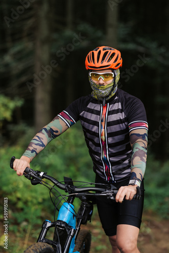 Mountain bike cyclist in sport equipment and helmet riding on rugged trails © JJ Studio
