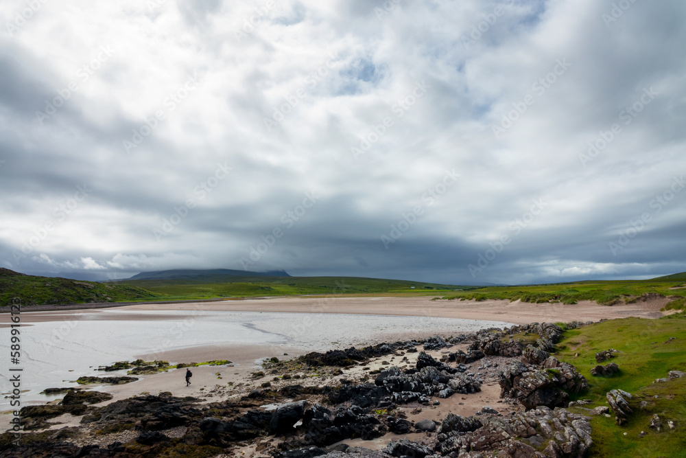 Lone man on a beach on Coigach peninsula in the north of Highlands, Scotland, UK Lone man on a beach on Coigach peninsula in the north of Highlands, Scotland, UK