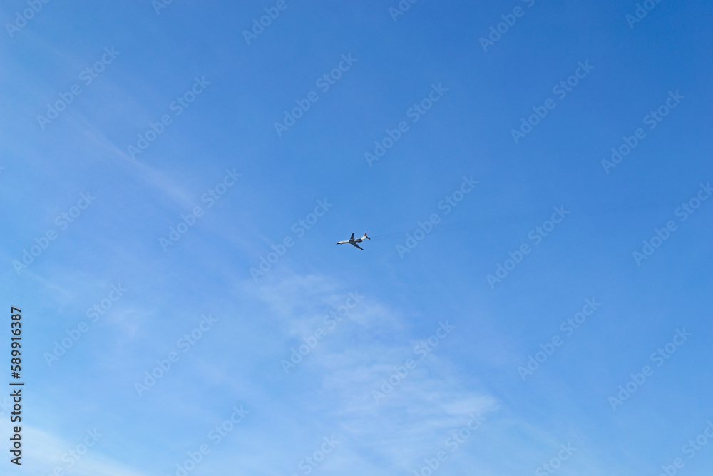The plane flies high in the blue sky with small clouds The plane flies high in the blue sky with small clouds