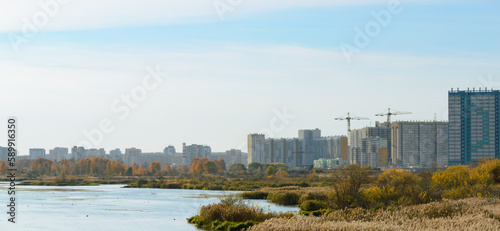 Panorama with river and nature and residential high-rise buildings in the distance © Maksim