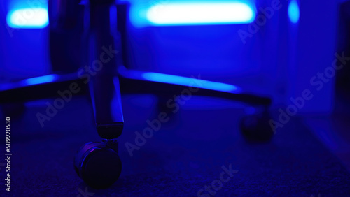 Gaming chair wheel base on soft carpet with neon lights in background