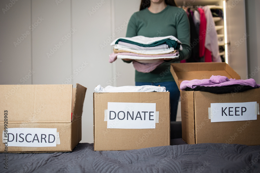 Woman no face packing her clothes in a moving box to donate clothes or