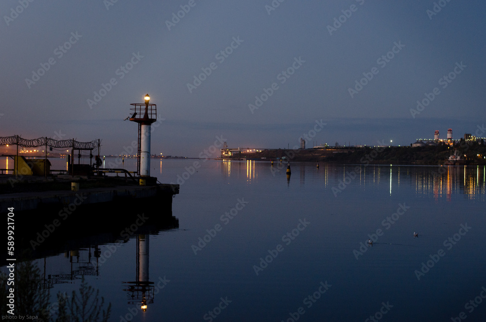 Seaport in a provincial town. Night. Port lights are reflected in the water.