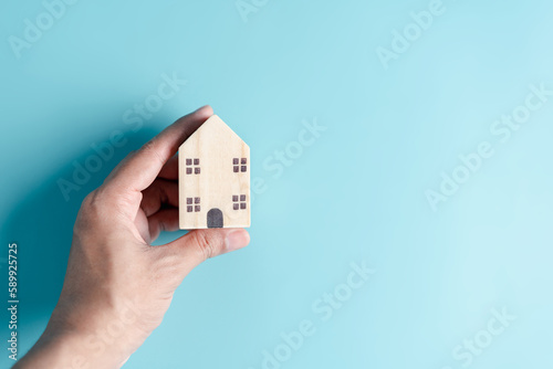 Hand holding wooden house, family home, homeless housing, mortgage crisis and home protection insurance, international day of families, foster home care, family day care, stay home concept