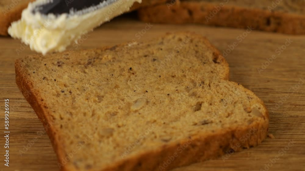 Cream cheese spread with a knife on a piece of multigrain bread on a wooden cutting board. Cream cheese spread with a knife on a piece of multigrain bread on a wooden cutting board.