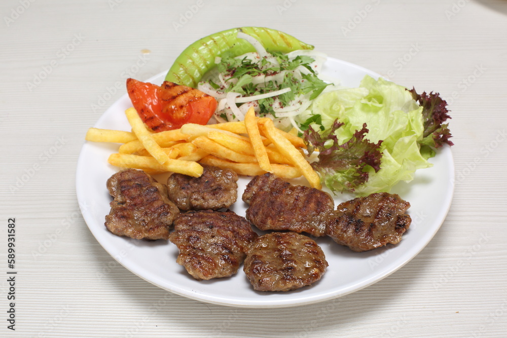 grilled meatballs served with fries and green salad grilled meatballs served with fries and green salad