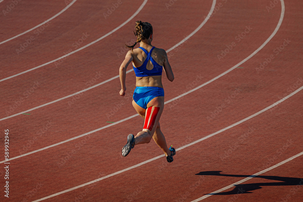 female runner running on red track stadium, kinesiotaping on back thigh, typical injury for sprinter athletes