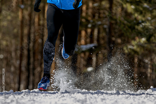 man running snowy trail in forest, splashes of snow from under your feet