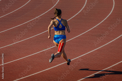 female runner running on red track stadium, kinesiotaping on back thigh, typical injury for sprinter athletes