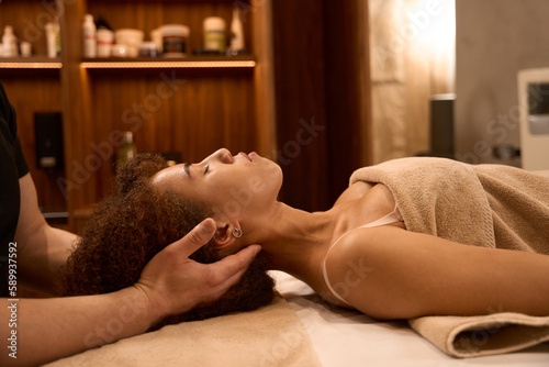 Young woman client lying on the massage desk in spa