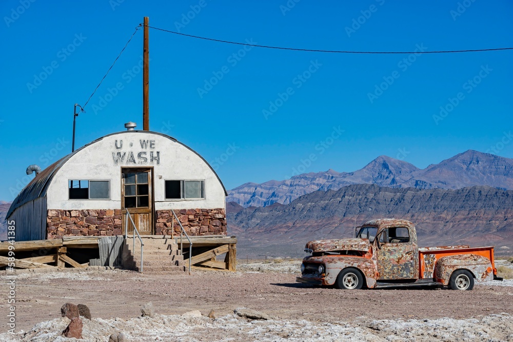 Sunny view of an abandoned house, car at Tecopa