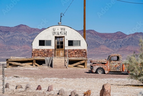 Sunny view of an abandoned house, car at Tecopa