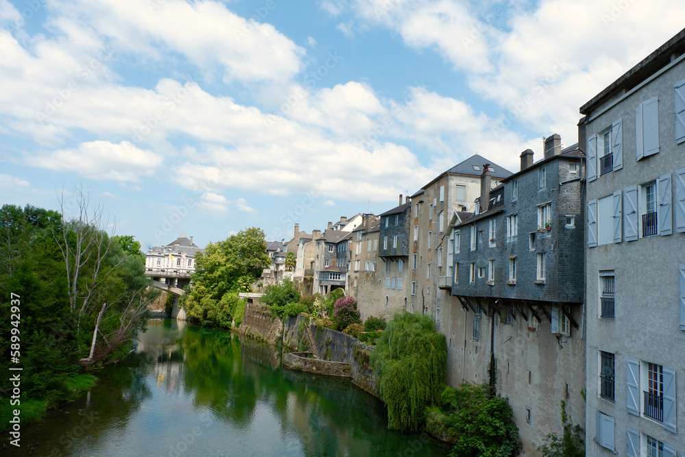 Vintage buildings and vivid greenery on the riverside of Oloron-Sainte-Marie at summertime in France