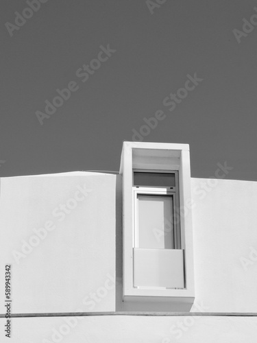 Simple lines of modern window on white facade view from outside in Portugal. Vertical black and white photo