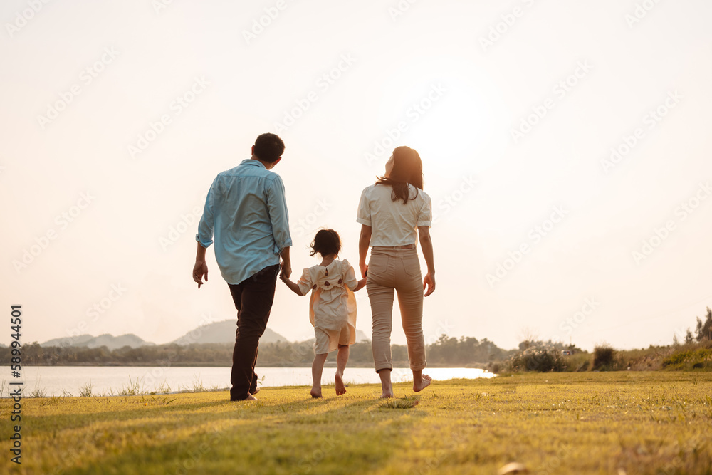 Happy Family enjoying a peaceful walk and running in a scenic field with a serene lake in the background.