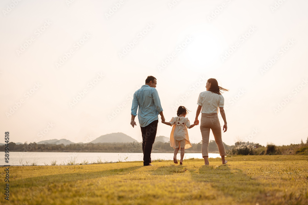 Happy Family enjoying a peaceful walk and running in a scenic field with a serene lake in the background. Happy Family enjoying a peaceful walk and running in a scenic field with a serene lake in the background.