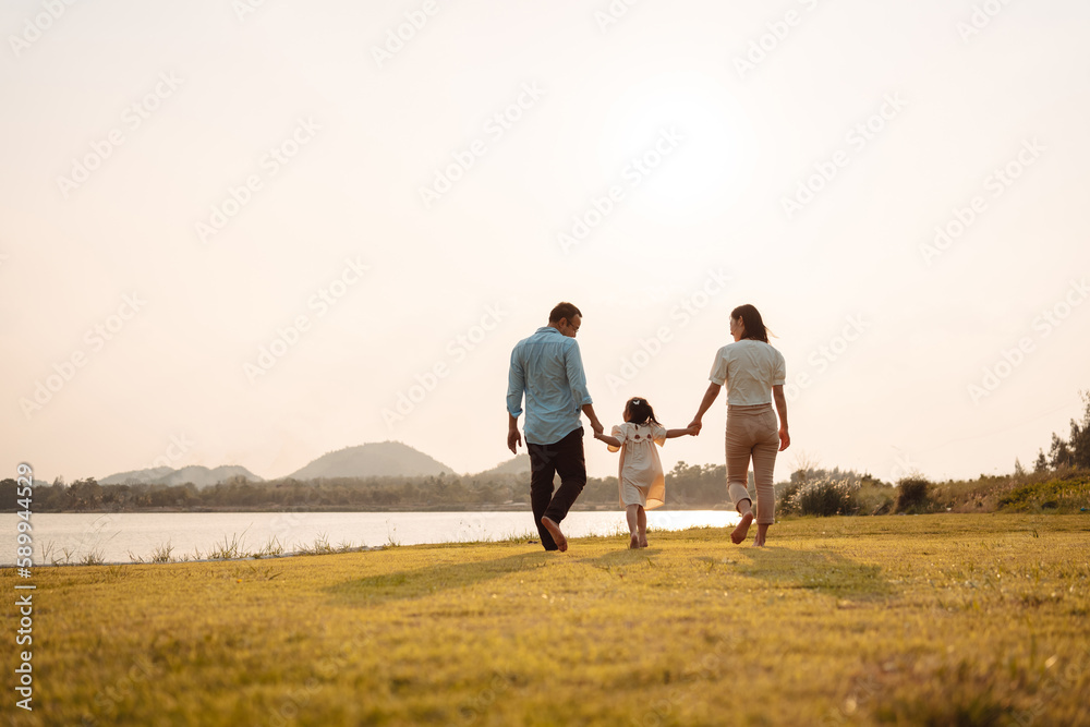 Happy Family enjoying a peaceful walk and running in a scenic field with a serene lake in the background. Happy Family enjoying a peaceful walk and running in a scenic field with a serene lake in the background.