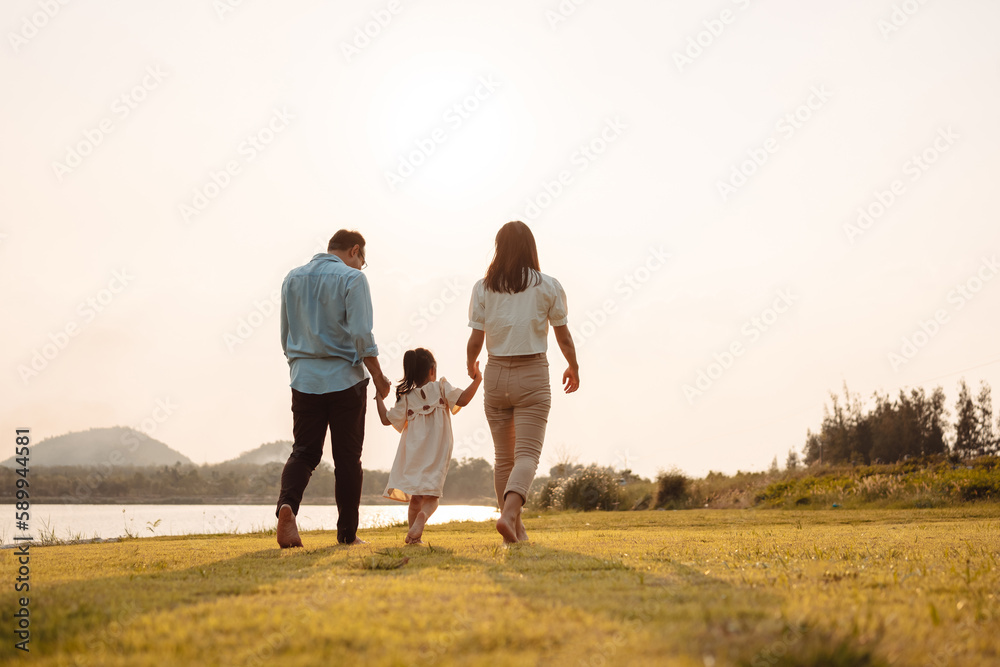 Happy Family enjoying a peaceful walk and running in a scenic field with a serene lake in the background.