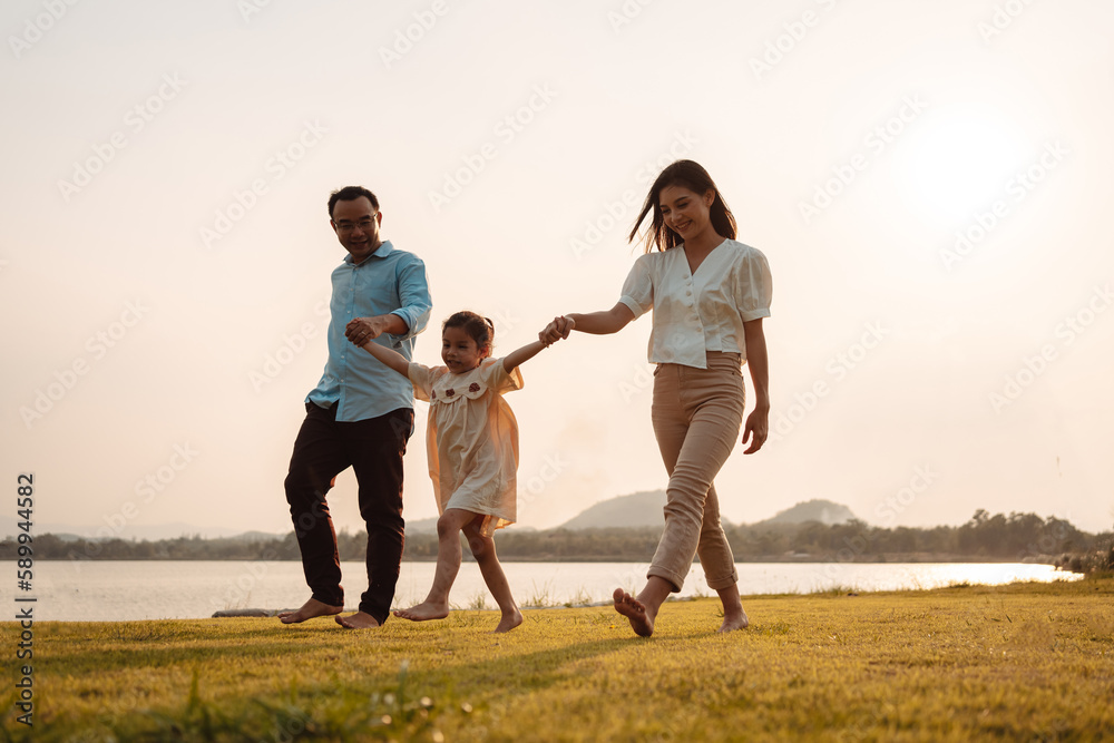 Happy Family enjoying a peaceful walk and running in a scenic field with a serene lake in the background. Happy Family enjoying a peaceful walk and running in a scenic field with a serene lake in the background.