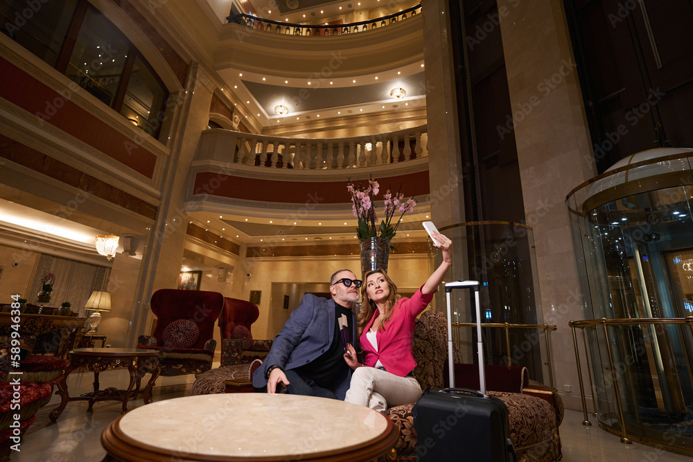 Traveling couple takes selfie in recreation area of luxury hotel