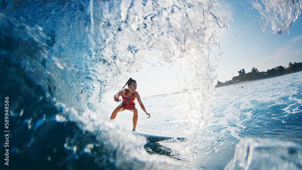 Girl surfer rides the wave. Woman in red suit surfs the ocean wave in the Maldives and gets barrelled