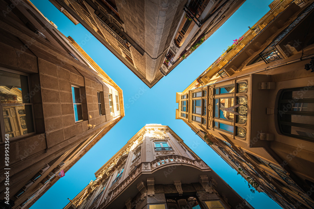 View from below of four buildings in the old town of Murcia with narrow streets and blue sky View from below of four buildings in the old town of Murcia with narrow streets and blue sky