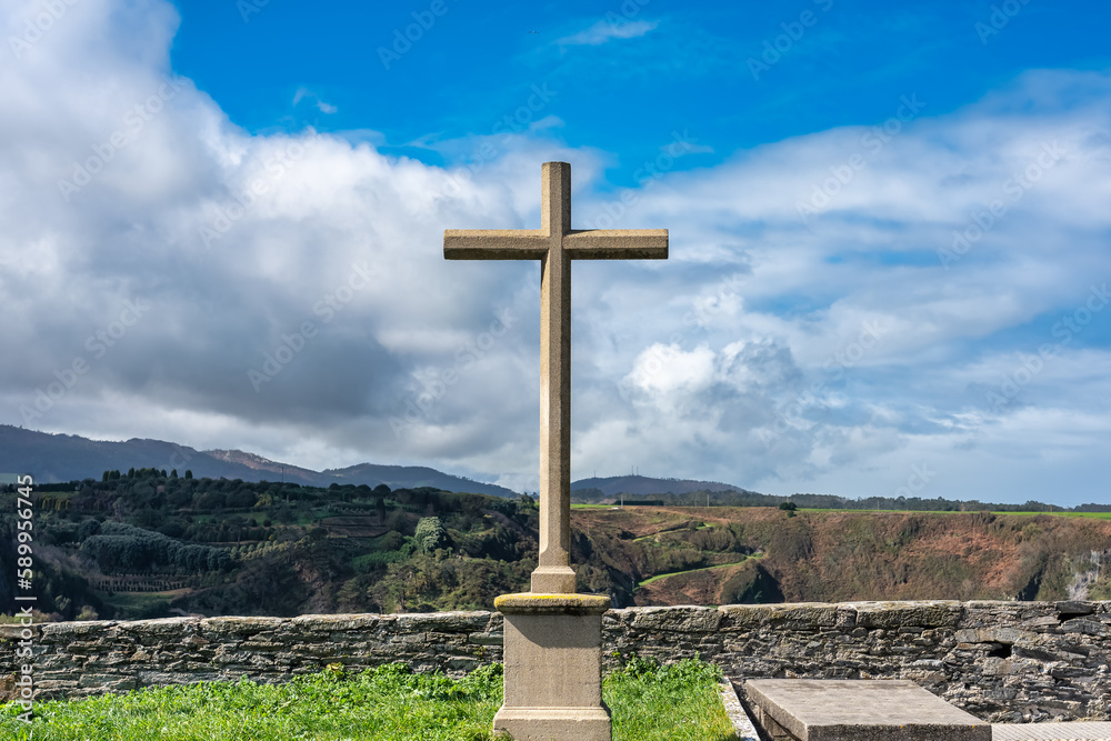 Stone cross in front of the cliffs of the Cantabrian Sea in the tourist town of Luarca, Asturias.
