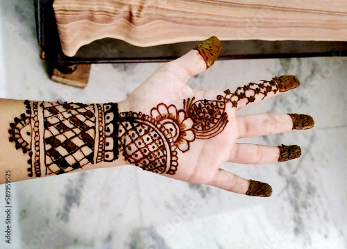 Beautiful artwork drawn on the hand of an Indian bride with herbal heena in wet condition. photo