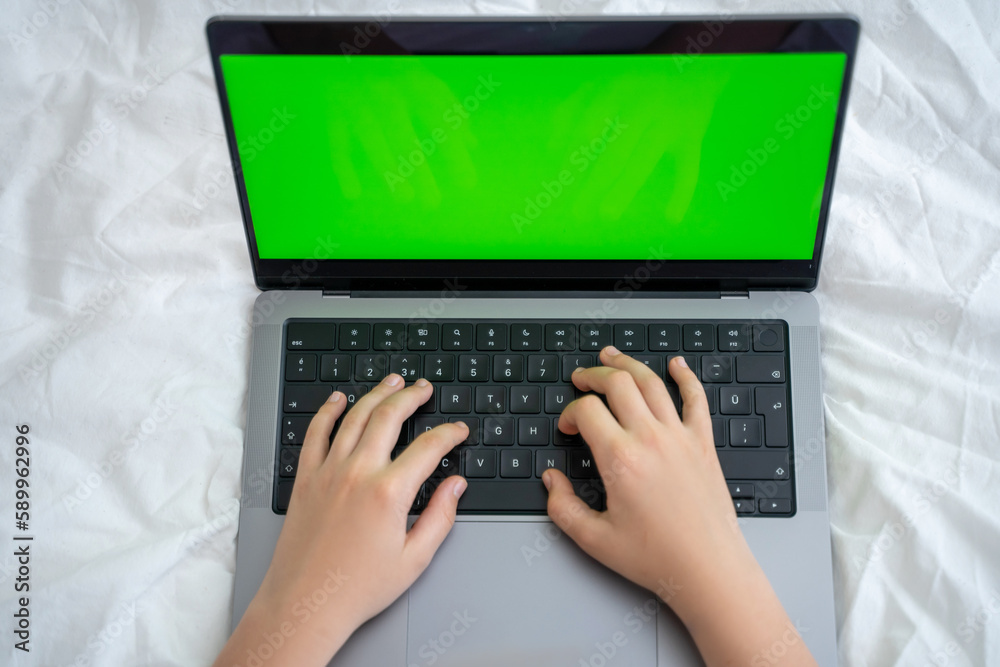 Close up smart caucasian middle School child using laptop green screen Chroma Key. Child typing on the keyboard. Online tutor teaching digital class, web lesson on computer at home. Virtual education