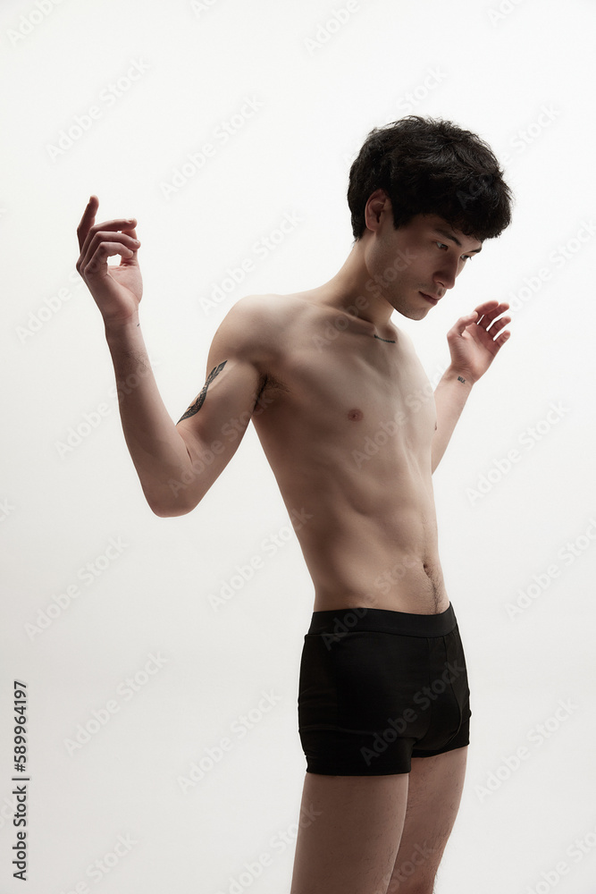 Portrait of young guy with slim, fit, relief body posing shirtless against  white studio background. Well-being. Art of body. Concept of male body  aesthetics, style, fashion, health, men's beauty Stock Photo