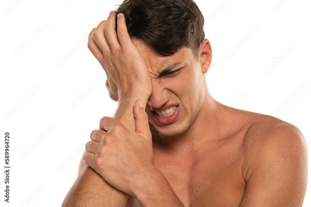 Closeup portrait of shirtless 20s man with eye pain isolated over white background Closeup portrait of shirtless 20s man with eye pain isolated over white background
