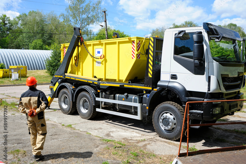 Worker watching radioactive waste storage container loading on a truck crane