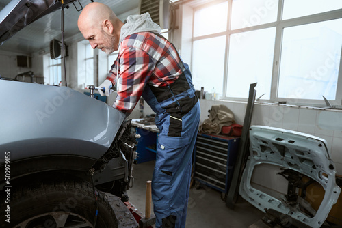 Auto repairman at the workplace repairs a car