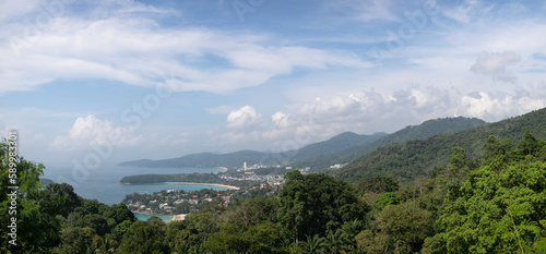 Panoramic view from the Karon viewpoint on Phuket Island. In the distance are Patong, Karon, Kata beach. Around are green hills covered with tropical jungle. Sunny, clear day, good weather.