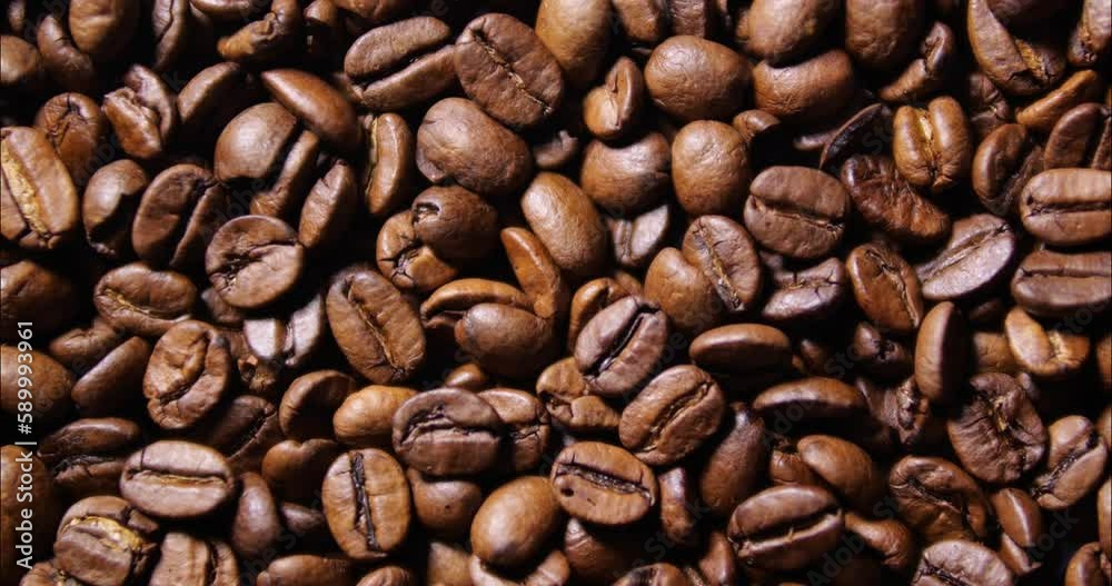 Roasted coffee beans close-up. Grains the coffee pours out and swirls in the container. A delicious hot drink product. Brown texture of coffee beans. Roasted coffee beans close-up. Grains the coffee pours out and swirls in the container. A delicious hot drink product. Brown texture of coffee beans.