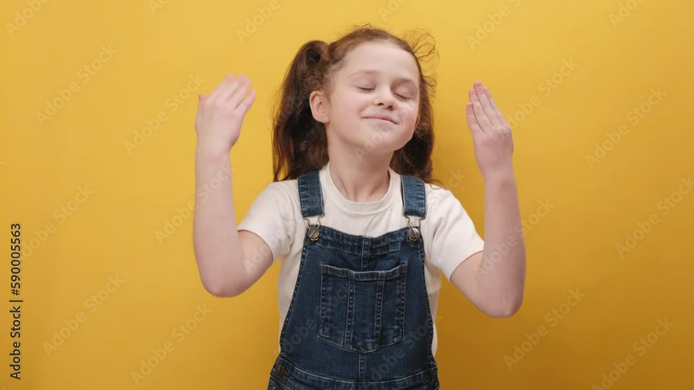 Portrait happy little girl stretching relaxing, smiling small child with eyes closed feel peaceful breathing fresh air, good pleasant smell, posing isolated on yellow color background wall in studio Portrait happy little girl stretching relaxing, smiling small child with eyes closed feel peaceful breathing fresh air, good pleasant smell, posing isolated on yellow color background wall in studio