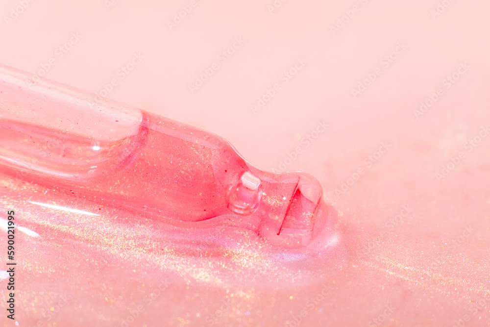 Fototapeta premium A cosmetic pipette lies in a pink liquid. Or rose gold liquid with sparkles. Laboratory research of cosmetics, gel, medicine. Chemistry